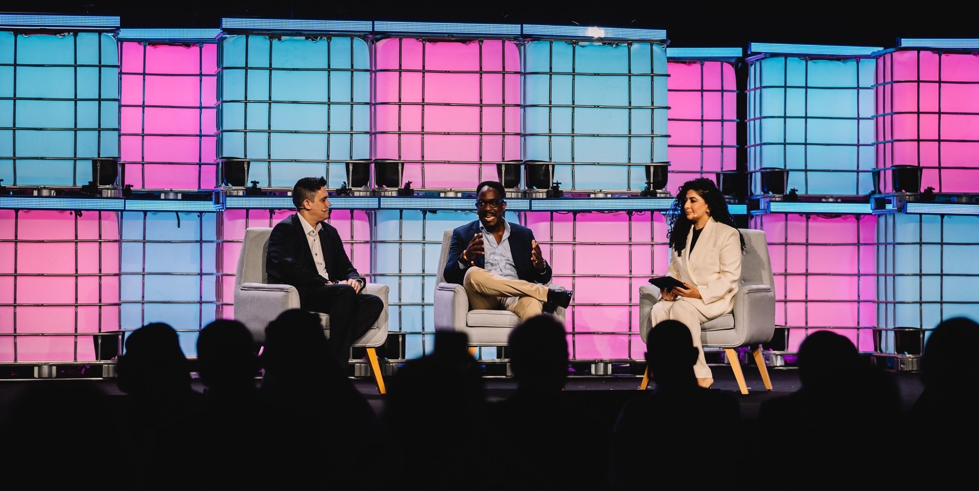 Conference panel on stage with colourful LED backdrop