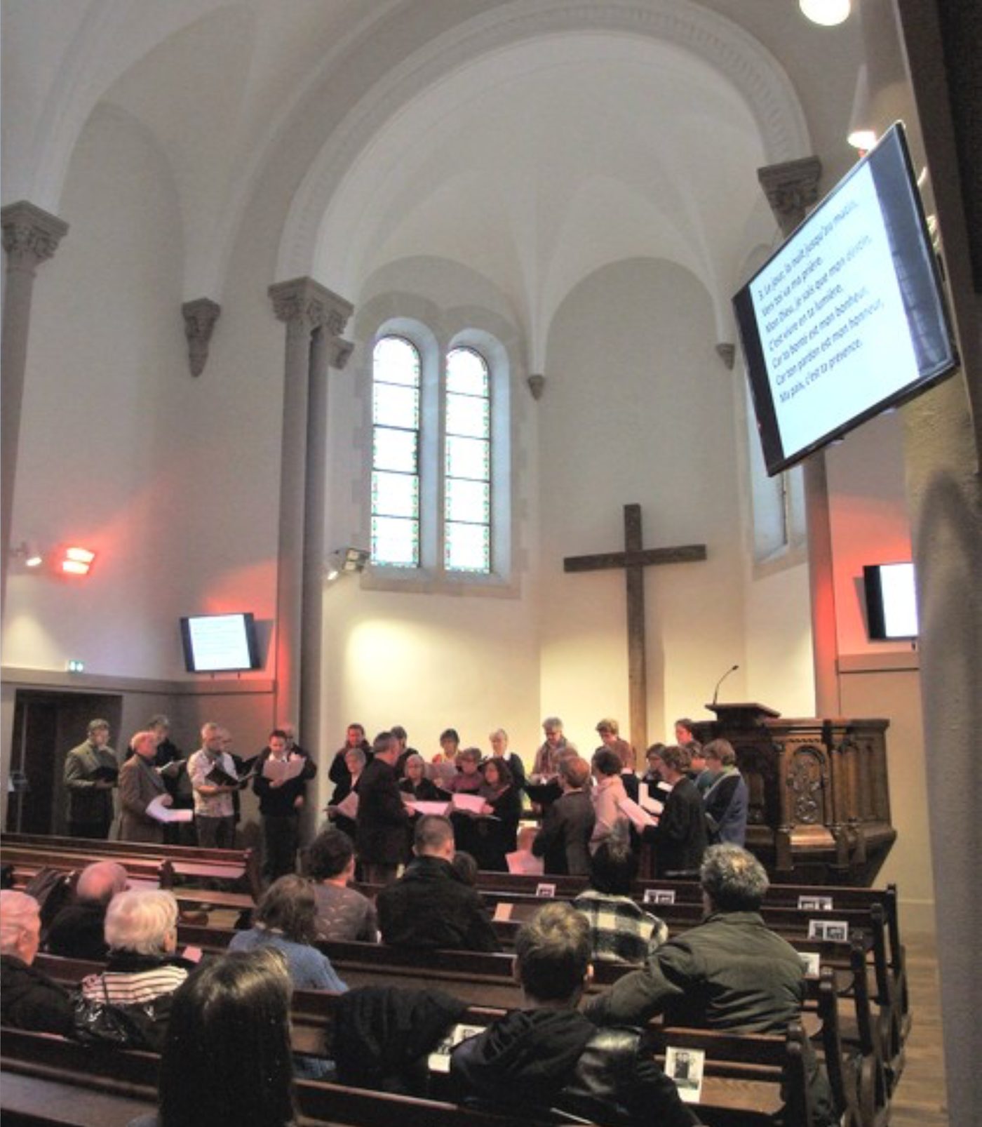 Service underway with captions displayed on screen, choir and congregation in the nave
