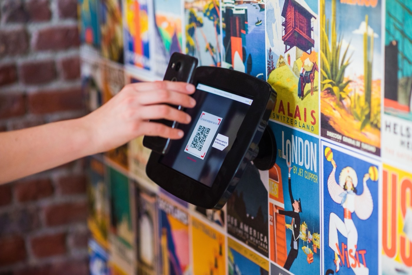 Visitor scanning a QR code with a smartphone in front of a display wall