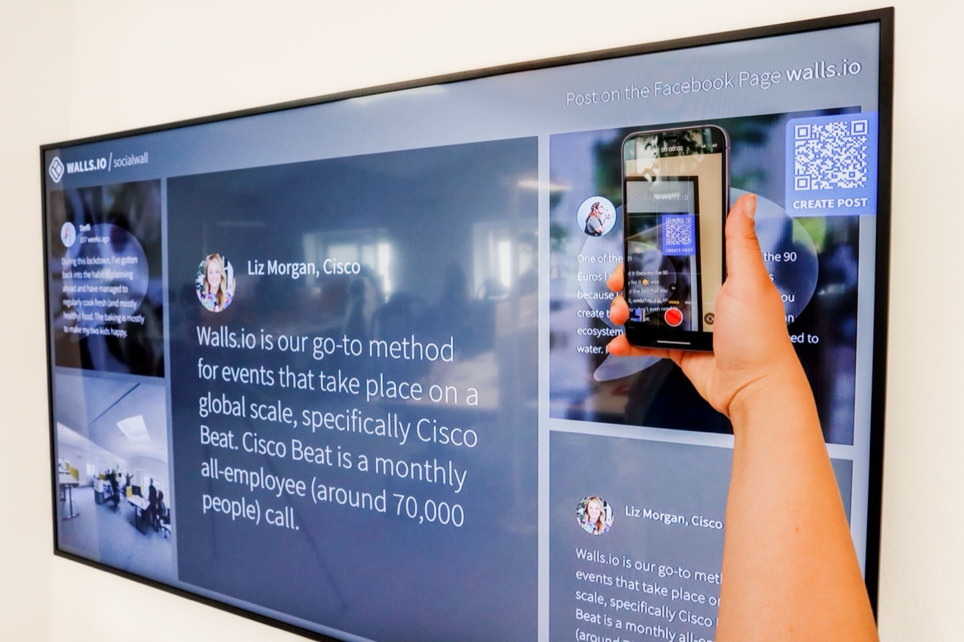 Person scanning a QR code shown on a wall-mounted screen