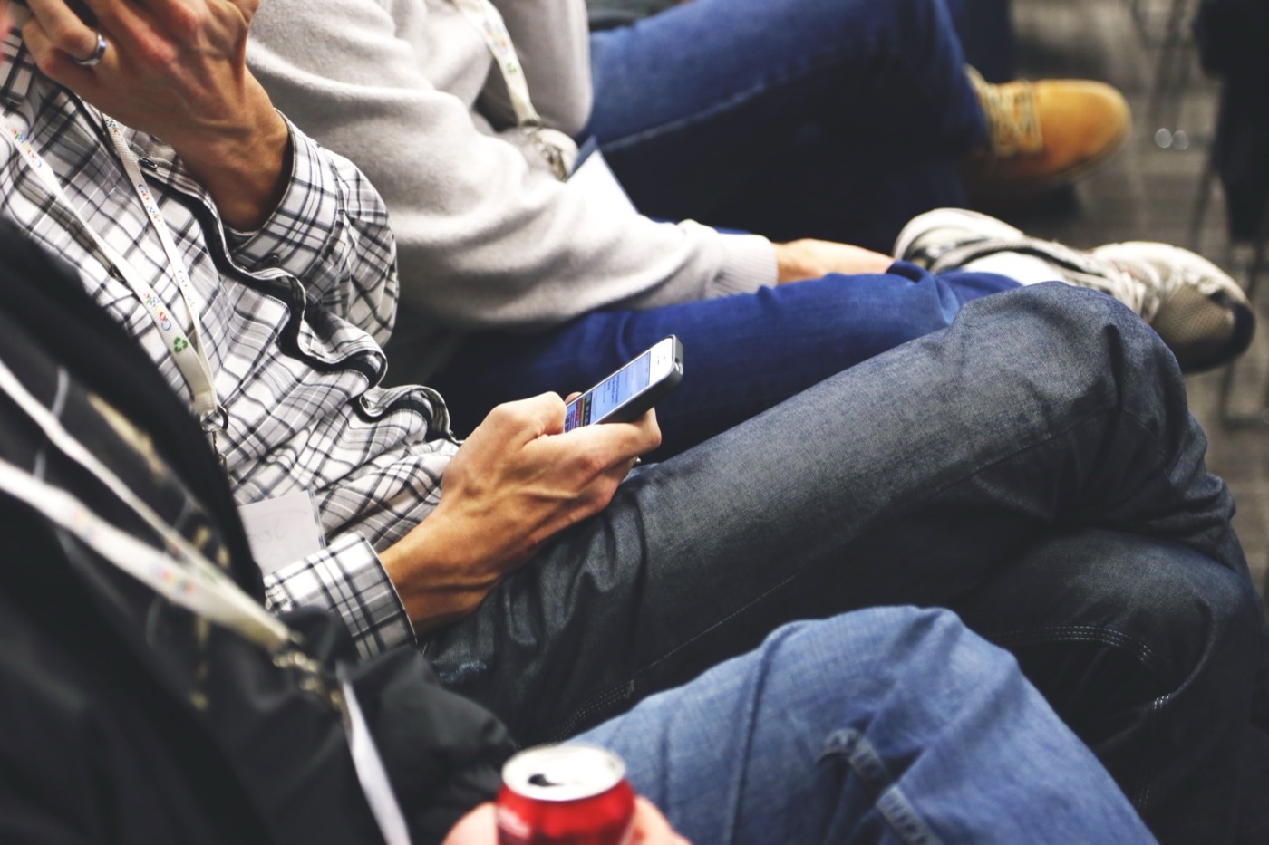 Conference attendees seated, one reading on a smartphone